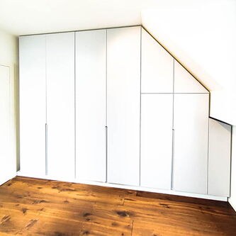 Tischlerei nipa Hamburg | weißer Einbauschrank unter Dachschräge eingepasst für Stauraumnutzung